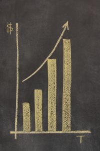 bar chart drawn on a chalkboard plotting time against money, with an arrow showing upward trend